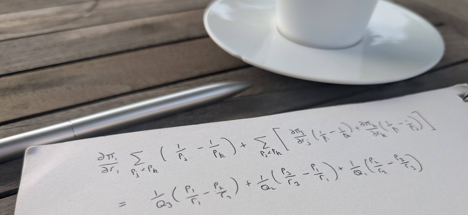 A handwritten price-optimisation equation beside a pen and an espresso on a sunny café table.